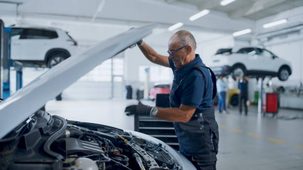 istock Senior Male Mechanic Examining Car Engine At Workshop 1892179634
