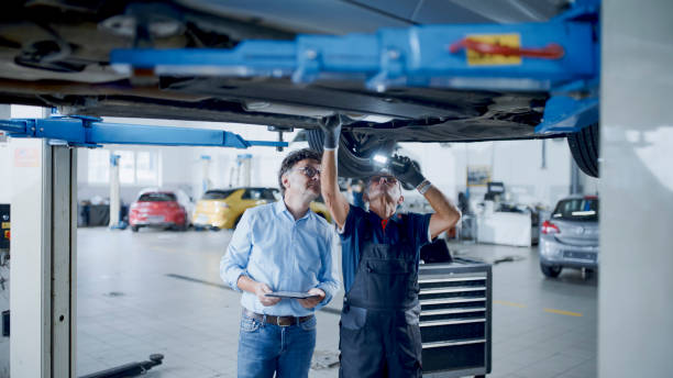 istock Male Mechanic And Manager Discussing Repairs Underneath Car At Workshop 1892179646