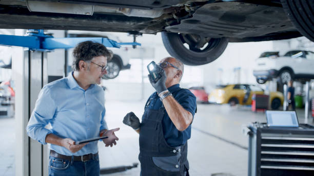 istock Male Mechanic And Manager Discussing Repairs Underneath Car At Workshop 1892180153