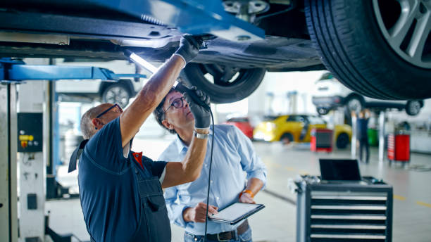 istock Male Mechanic And Manager Discussing Repairs Underneath Car At Workshop 1892180158