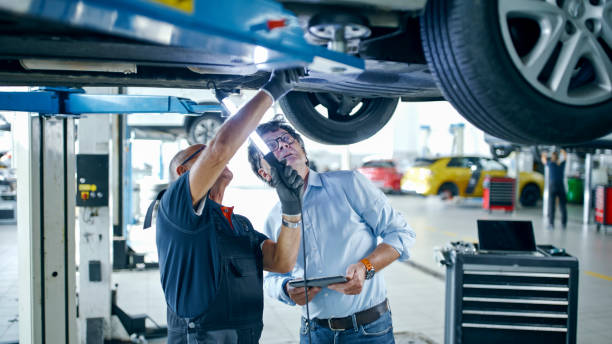 istock Male Mechanic And Manager Discussing Repairs Underneath Car At Workshop 1892180162