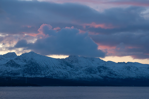 Purple and orange hues during a lightly clouded sunset over the arctic mountains, in Norway