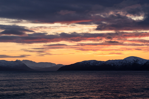 Sunset over the fjords of Norway, beautiful cloud cover and color over the ocean, purple clouds over golden sunset