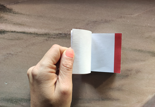 Miniature book in hand against textured background