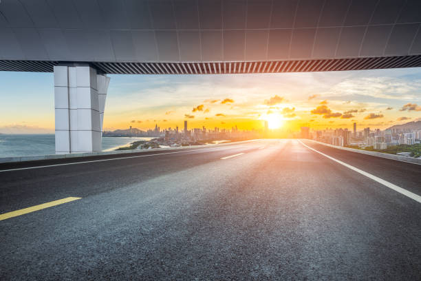 istock Empty asphalt road and city buildings skyline at sunset 1892249452