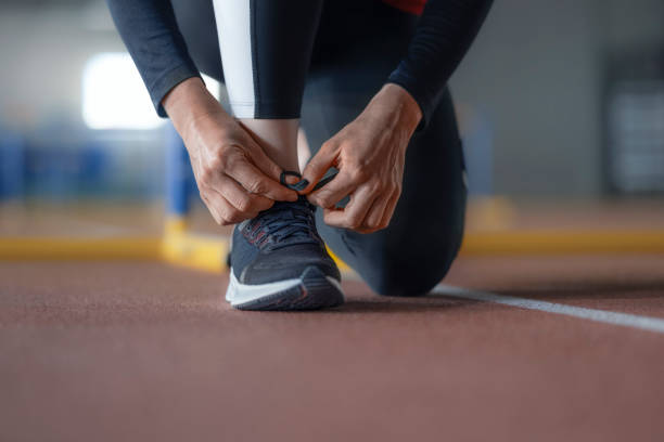 istock Female athlete's hand tying shoelaces 1892280385
