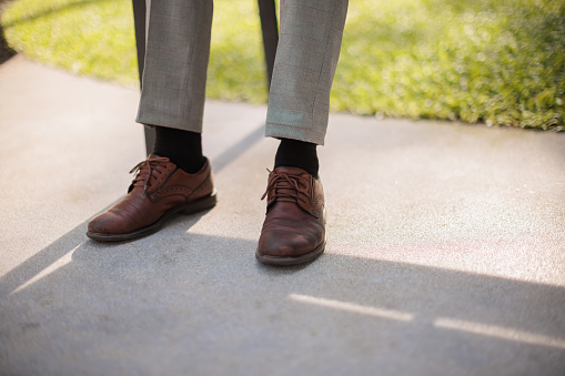 Low section of a man dressed in a suit showcases his shoes.