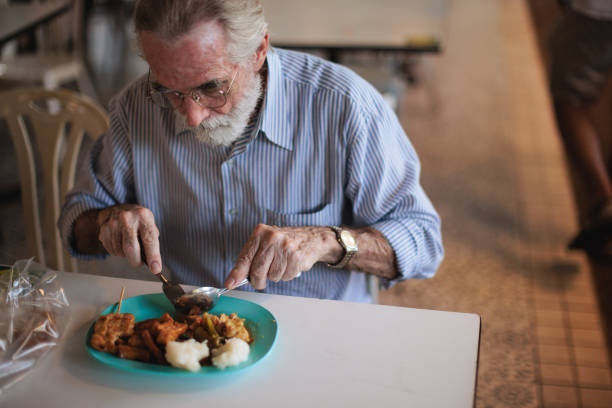 Senior man enjoying local Thai food at the food court in Bangkok.