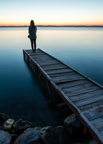 Women standing on jetty, at sunset, in summer