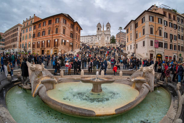 Rome, Lazio, Italy - December 28, 2023: Piazza di Spagna is one of the most famous and visited squares in Rome.  In the center stands the Barcaccia Fountain, designed and sculpted in Baroque style by Bernini.  In the background the Trinità dei Monti staircase