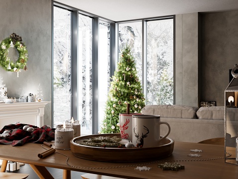 New Year's Day Morning. Macro of Christmas interior view with hot chocolate and cookies on wooden table. Scandinavian Style large green Christmas tree by the panoramic window.