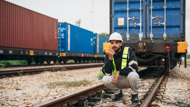 istock Foreman checking inventory or task details on freight train cars and shipping containers. Logistics concept, import, and export industries. 1892464328