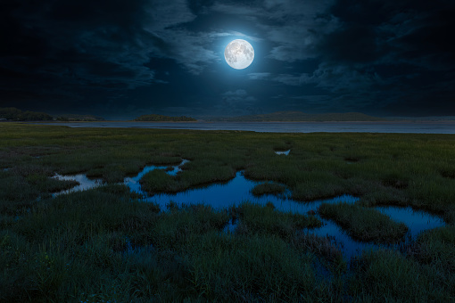 Digital composite of night view over the salt marshes towards Morecambe Bay from Grange-over-Sands in Cumbria, England.