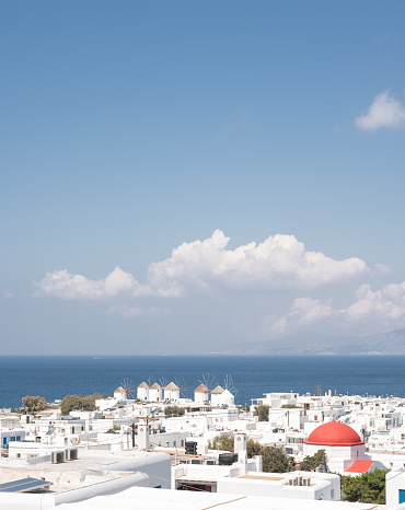 Panoramic view of Mykonos town and windmills. White houses, blue sea and hills at dawn.