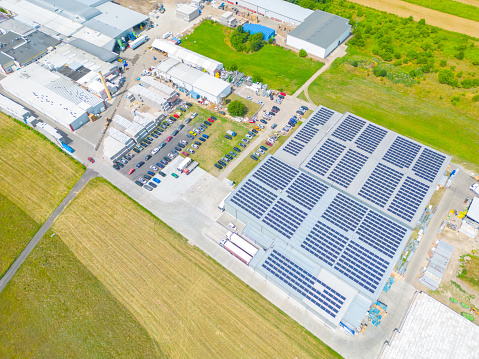 Industry with low carbon footprint. Industrial warehouses with solar panels on the roof. Technology park and factories from above.