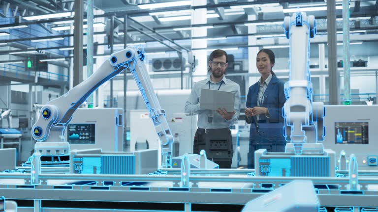 Electronics Factory Digitalization: Automated Robot Arm Assembly Line Manufacturing Advanced Equipment. Managers Discussing Work while Futuristic AI Computer Vision Analyzing, Scanning Production Line