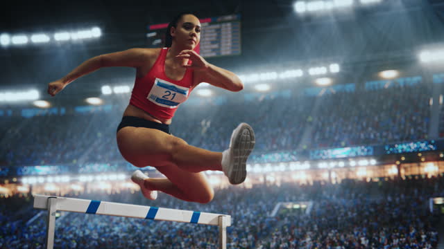 Sports Footage with Super Slow Motion Speed Ramp Effect. Talented Female Hurdler Jumping Over Obstacle, Racing Against Time and Setting a New Sprint Record in Front of a Stadium with Cheering Fans