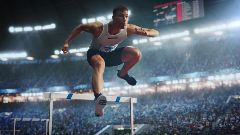 Sports Footage with Super Slow Motion Speed Ramp Effect. Talented Male Hurdler Jumping Over Obstacle, Racing Against Time and Setting a New Sprint Record in Front of a Stadium with Cheering Fans