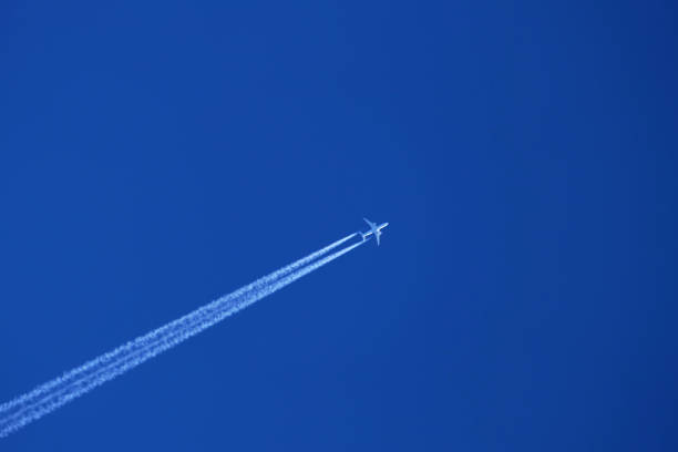 istock Airplane in the blue sky with contrail 1892576876