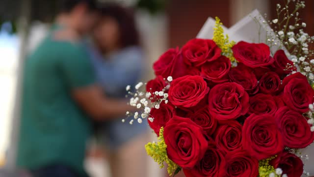 Close-up of a bunch of flowers and a couple embracing in the background - Valentine's Day