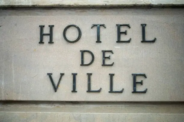 Photo of french city hall signage on stoned building facade, with text in french, hotel de ville, traduction in english : city hall