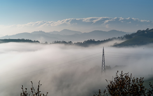 view of electric pylon in fog against mountains and sky