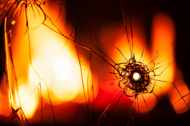 Eruption of Destruction: A Bullet Hole Piercing Through Glass Amid Flames