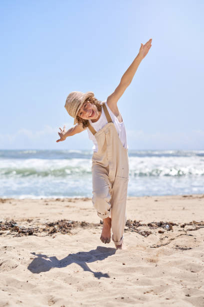 Cheerful boy running on beach with hands wide open like airplane