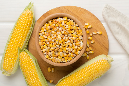 Dry corn with fresh cobs on wooden background, top view