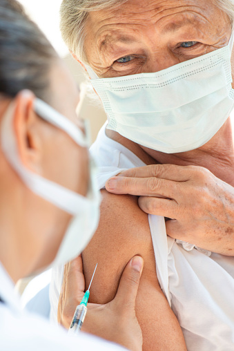 Nurse applying vaccine on senior woman.