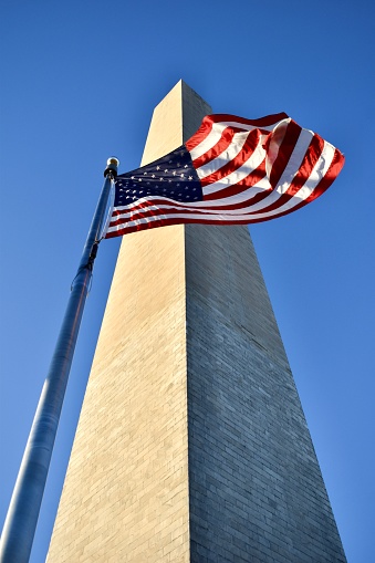 A waiving American flag in front of the Washington monument