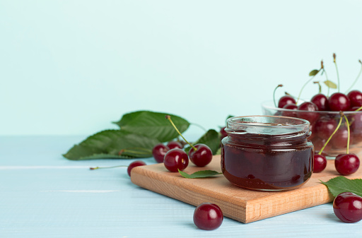 Jar with tasty homemade cherry jam on wooden table