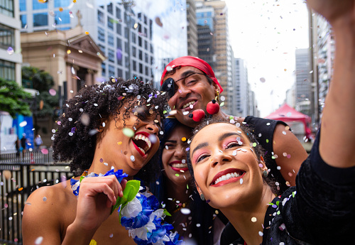 Girls taking selfie at street party parade, brazilian carnaval. Group of Brazilian friends in costume celebrating.