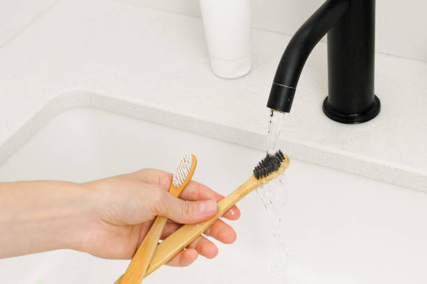 istock A woman's hand washes wooden bamboo toothbrushes from toothpaste after brushing teeth under a stream of water over a sink. Concept of oral hygiene and natural cosmetic products, sustainable lifestyle 1892842659