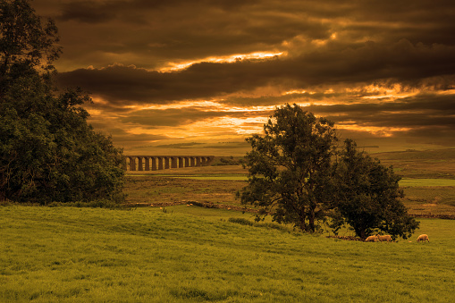 Digital composite sunset image of the Ribblehead Railway Viaduct in the Yorkshire Dales National Park, England.