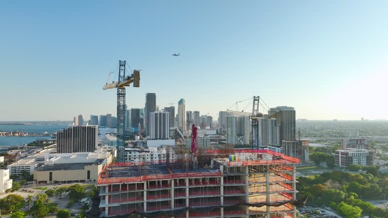 New construction site of developing residence in American urban area. Industrial tower lifting cranes in Miami, Florida. Concept of housing growth in the USA