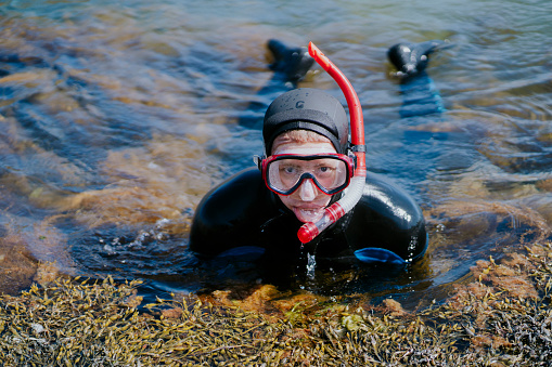 Captivating portrait: A person dons a scuba mask while snorkeling, merging style with adventure in the underwater realm.