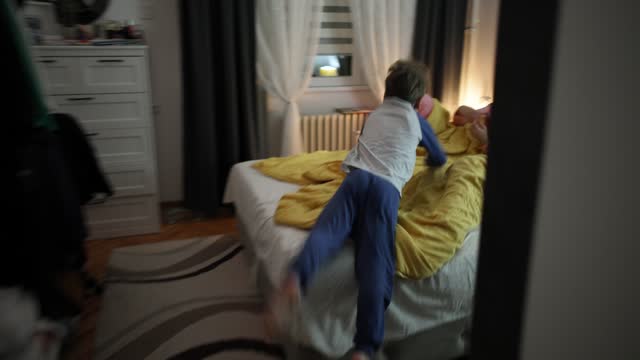 Boy jumping and playing in the bed with his parents