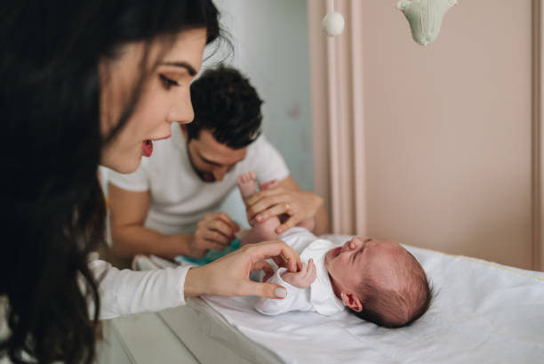 istock Mother talking to her newborn daughter while father changes her diaper at home 1892956754