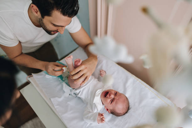 istock Father changing his newborn daughter's diaper at home 1892956755