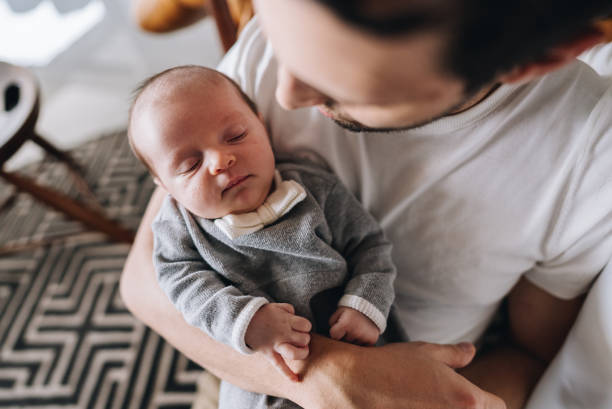 istock Newborn baby sleeping on her father's lap at home 1892959453