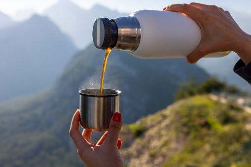 Pouring fresh coffee to the cup at the mountain