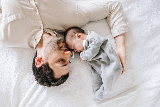 istock Father looking at his newborn daughter while sleeping in bed at home 1892964141