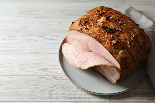 Delicious baked ham on white wooden table. Space for text