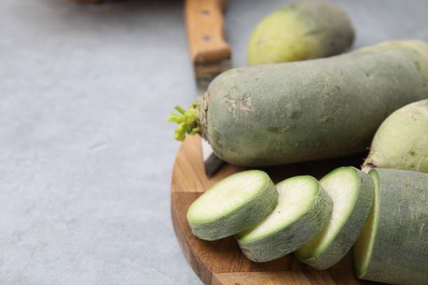 istock Green daikon radishes and knife on light grey table, closeup. Space for text 1893009231