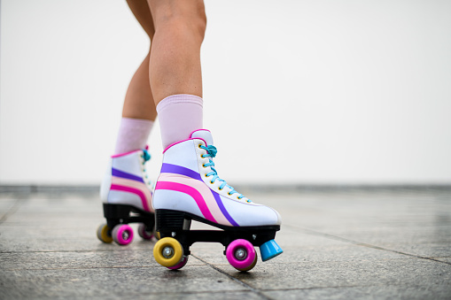 Cropped photo of female legs in colorful vintage roller skates shoes isolated on white wall background. extreme balance concept, street outside urban lifestyle