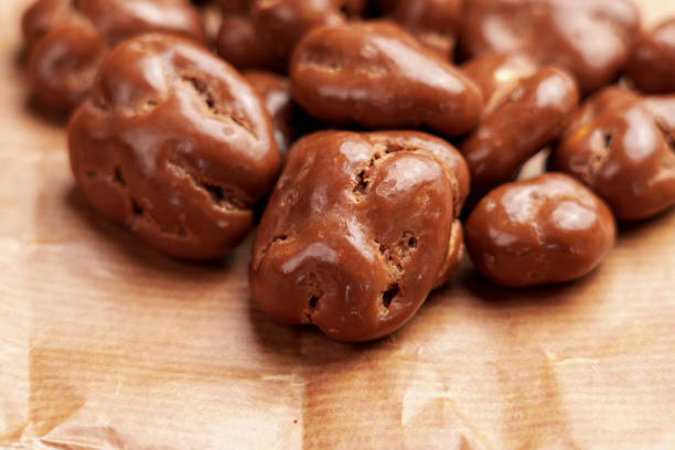 istock Glazed chocolate nut candy with dried walnuts on a brown package paper. 1893087114