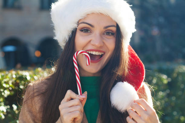istock Young woman eating a Christmas candy cane 1893095821