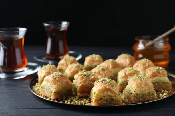 istock Delicious fresh baklava with chopped nuts on black wooden table. Eastern sweets 1893106706