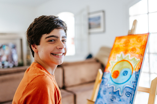 Portrait of a teenage boy next to his freshly painted canvas